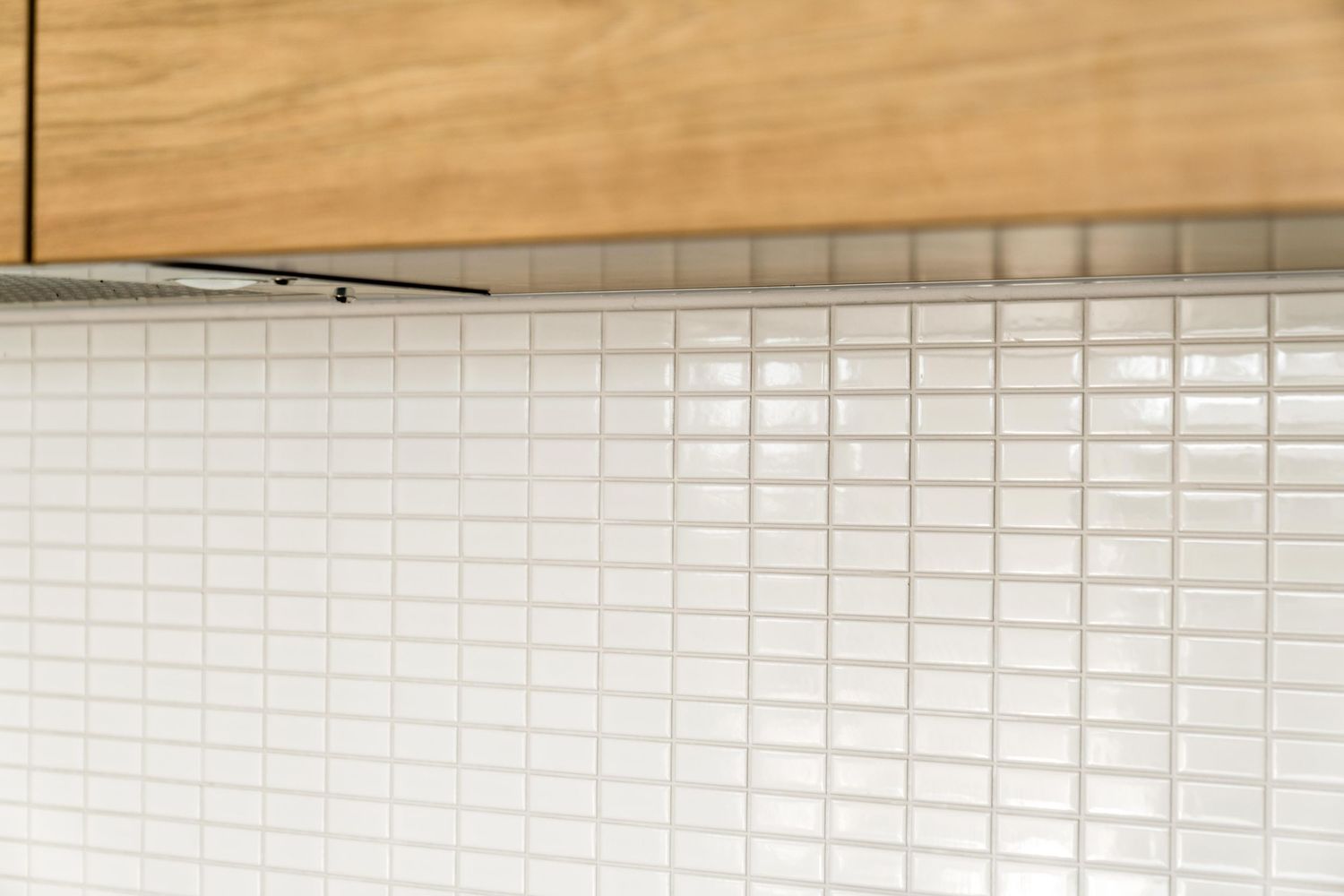 Modern kitchen interior featuring white subway tile backsplash, wood cabinets, and built-in appliances.