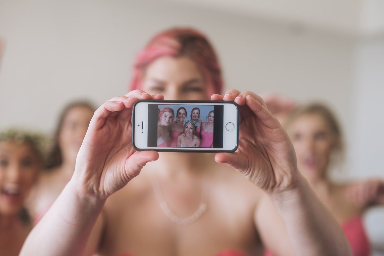 Hands hold up a smartphone displaying a group photo during a celebration.