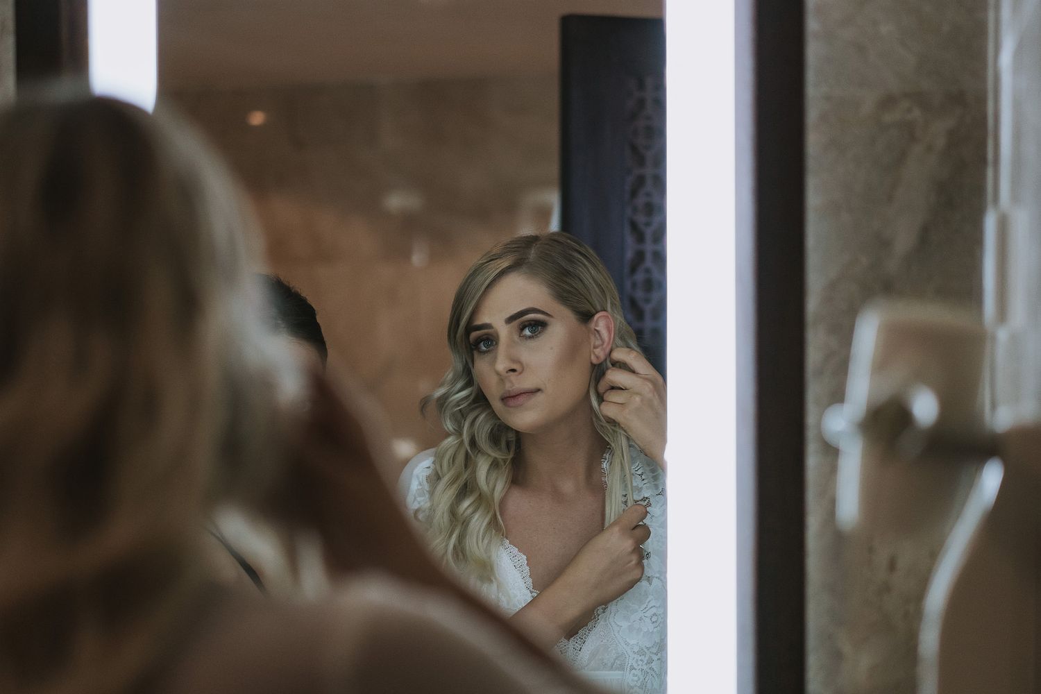 Reflective beauty preparation scene in soft lighting with multiple mirror angles showing elegant styling.