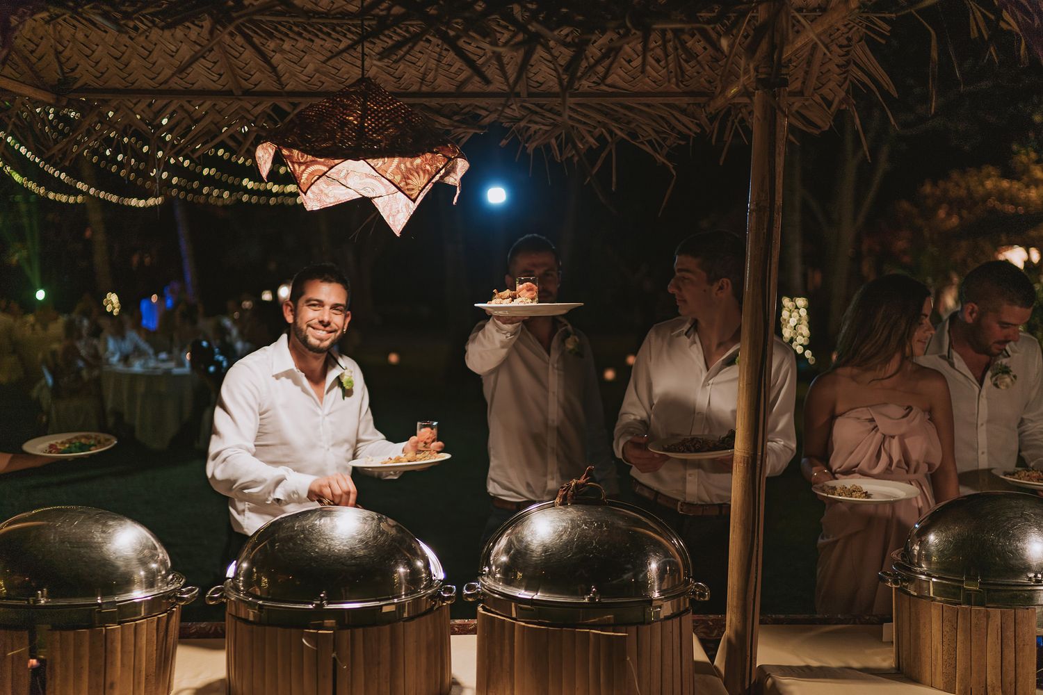 Guests enjoying an intimate evening outdoor wedding reception with warm lighting and string lights.