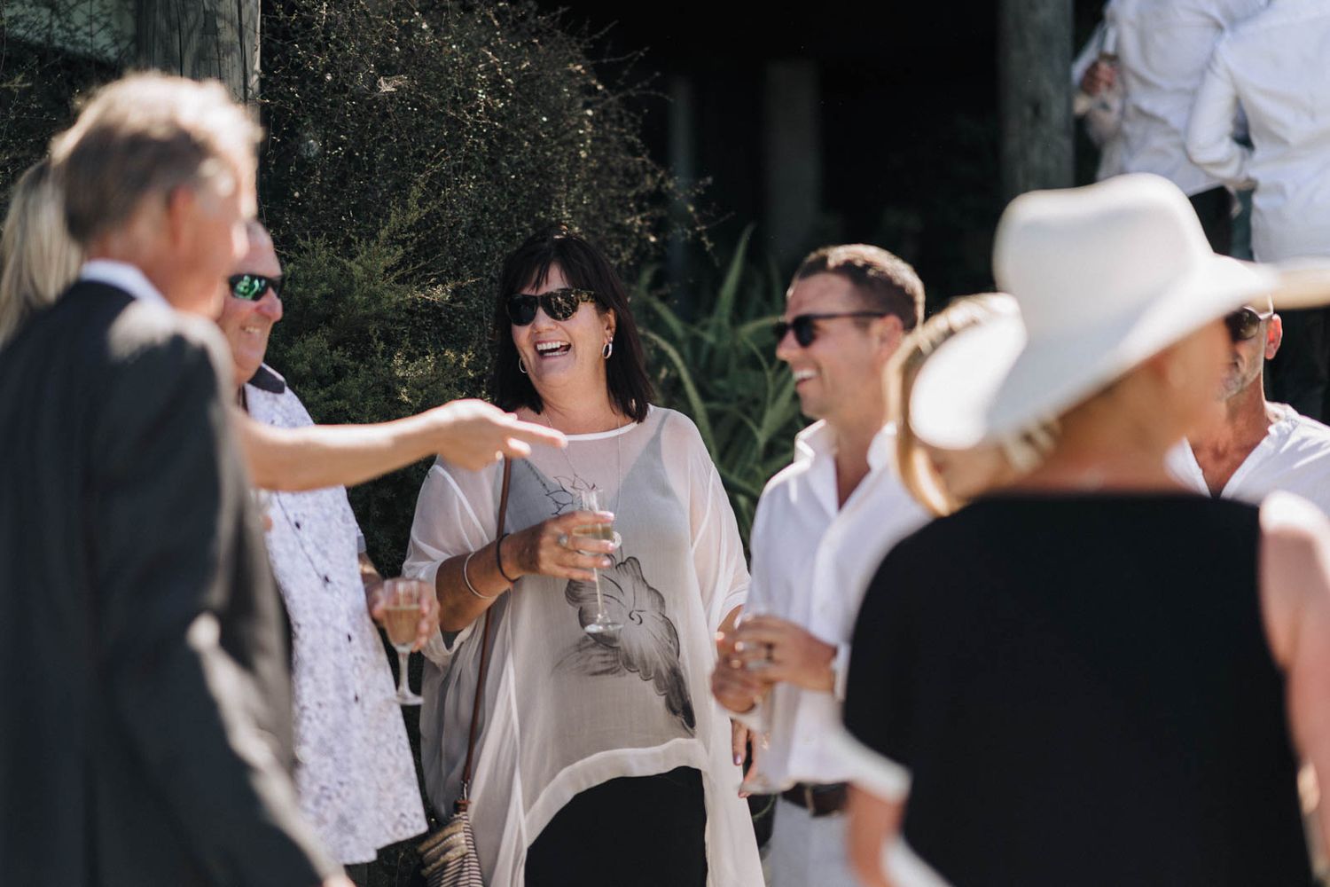 A group of people mingle outdoors during what appears to be a summer social gathering.