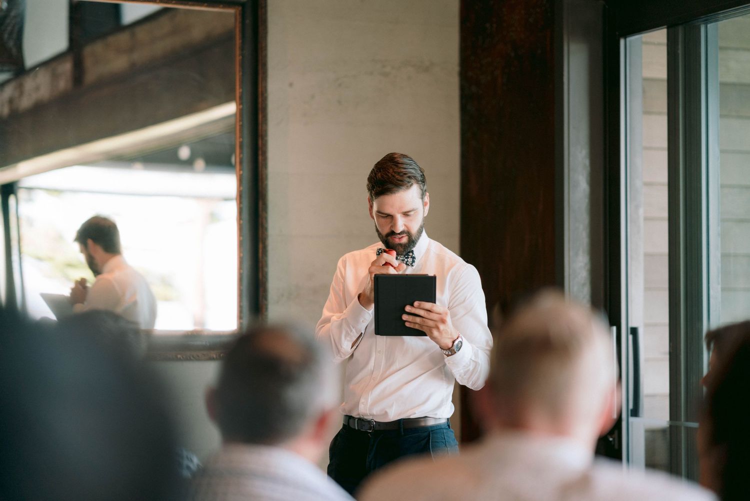 Person adjusting necktie while getting ready in front of window reflection.