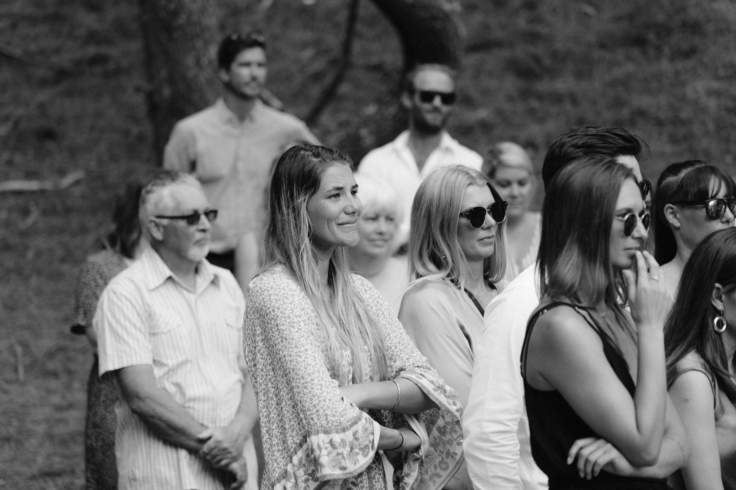 A group of wedding guests in black and white attire gathered outdoors for socializing and celebration.