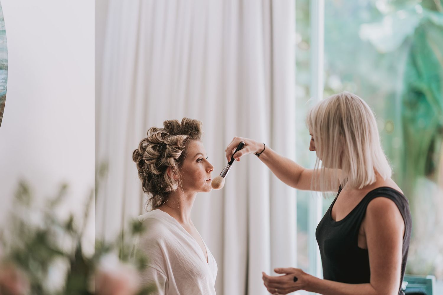 Professional hairdresser working on styling and preparing client's hair in bright salon setting.