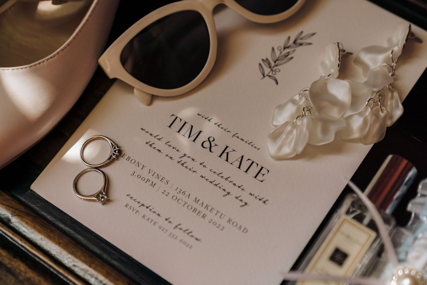 Wedding invitation with sunglasses and jewelry details in soft lighting.