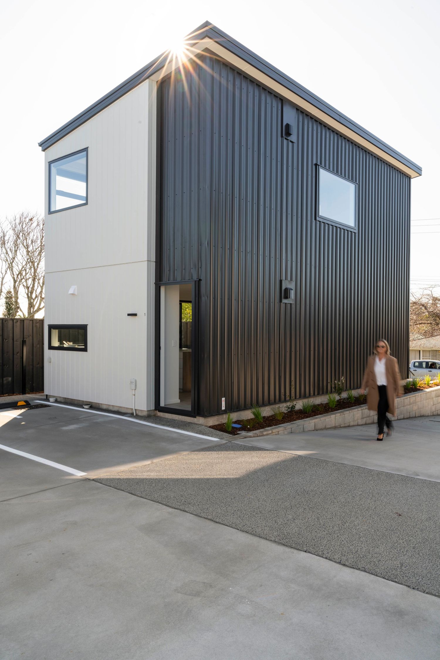 Modern black and white commercial building with angular roof lines features large windows and clean architectural design.