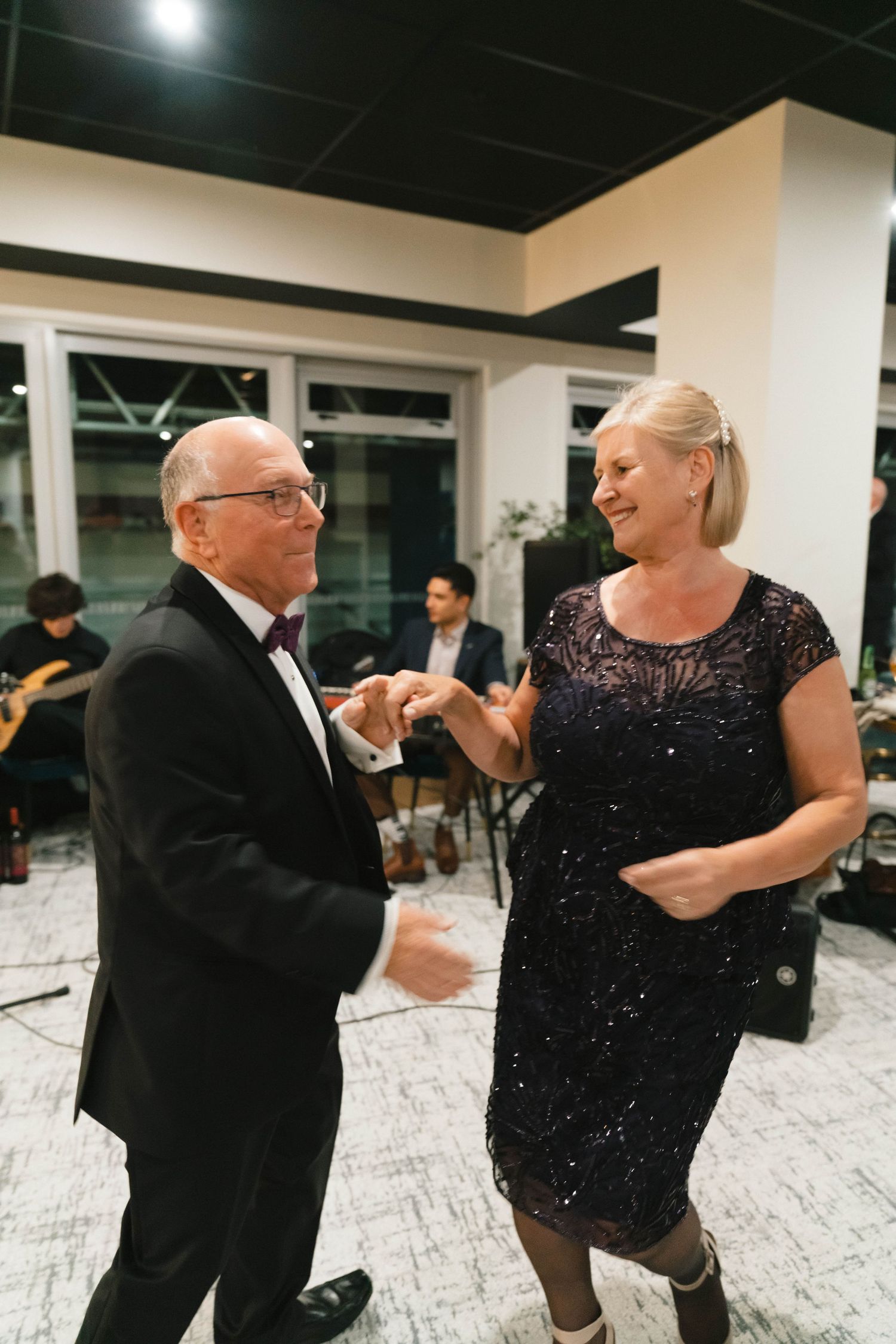 Couple dancing together at formal event, woman wearing sparkly black dress.