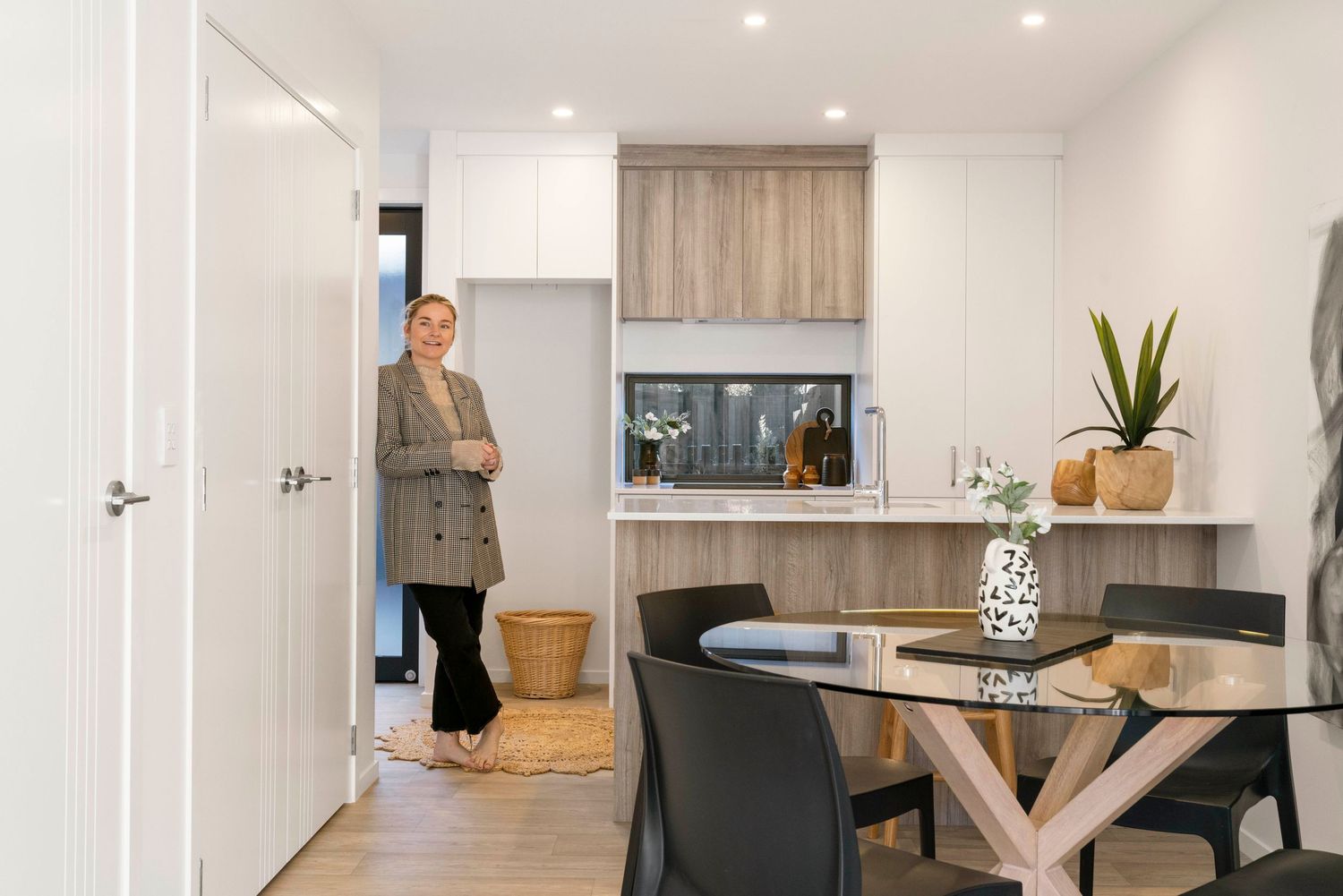 Modern white kitchen with wooden accents featuring a round dining table and black chairs.