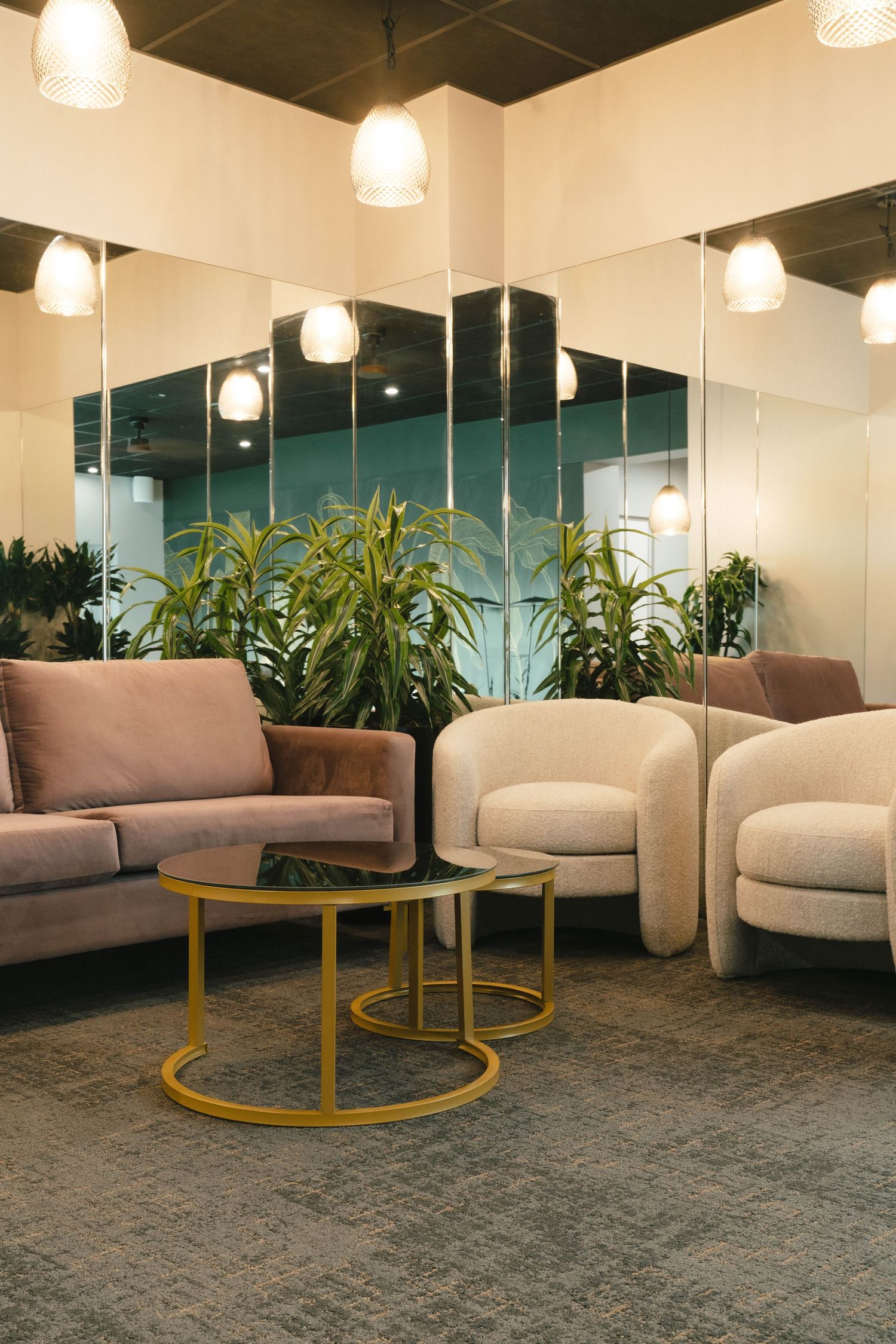 Modern lounge area with grey couches and yellow circular coffee tables in a well-lit office space.