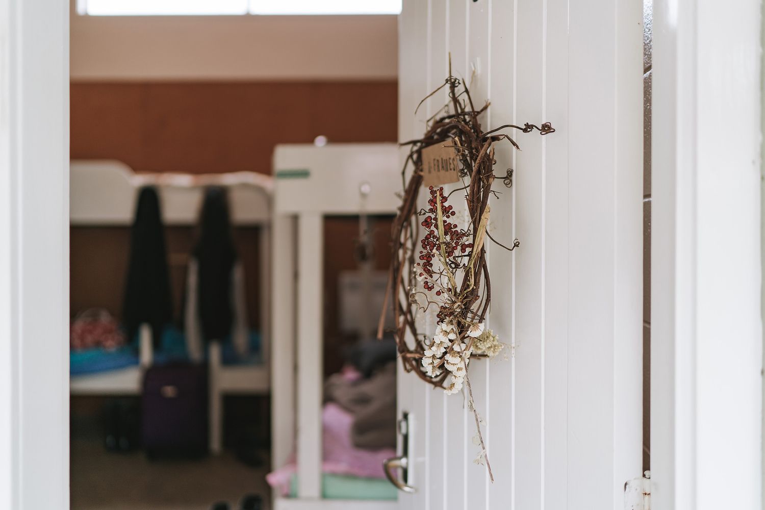 A dried floral arrangement hanging from a white door frame in a softly lit interior room.