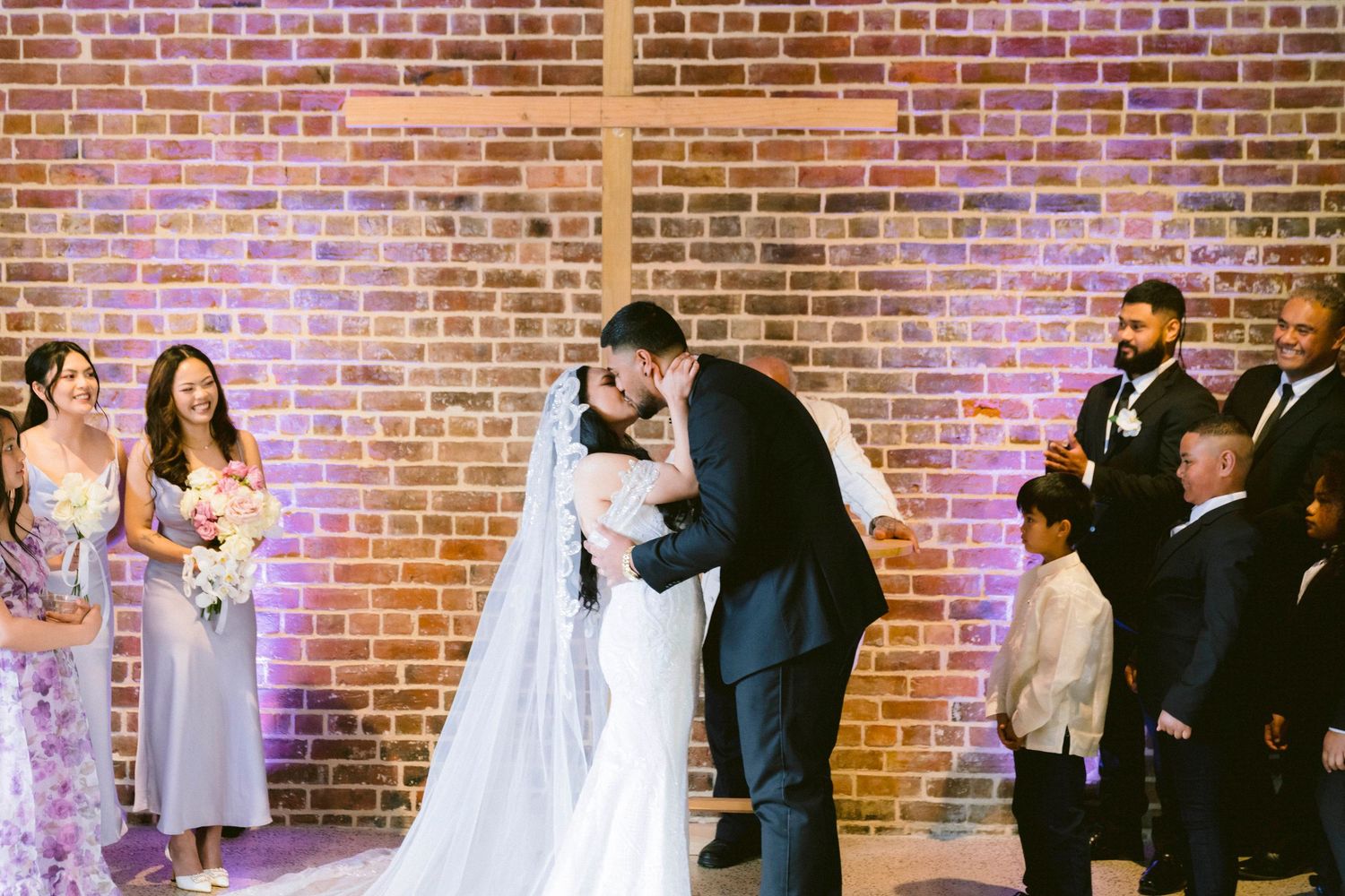 Wedding celebration sequence against a brick wall with colored uplighting showing the couple and wedding party.