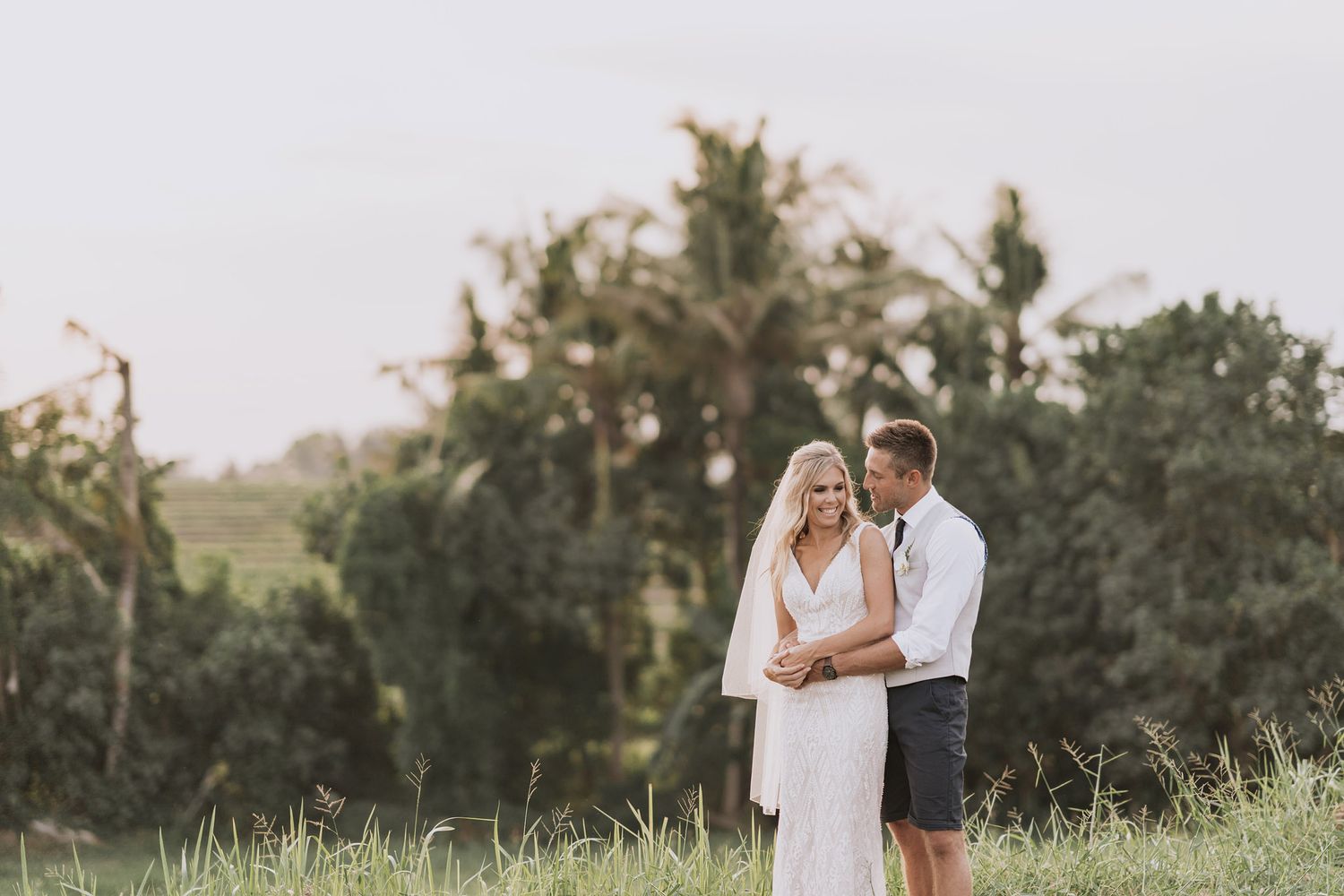 A romantic moment captured between a couple in wedding attire against a natural tropical backdrop.