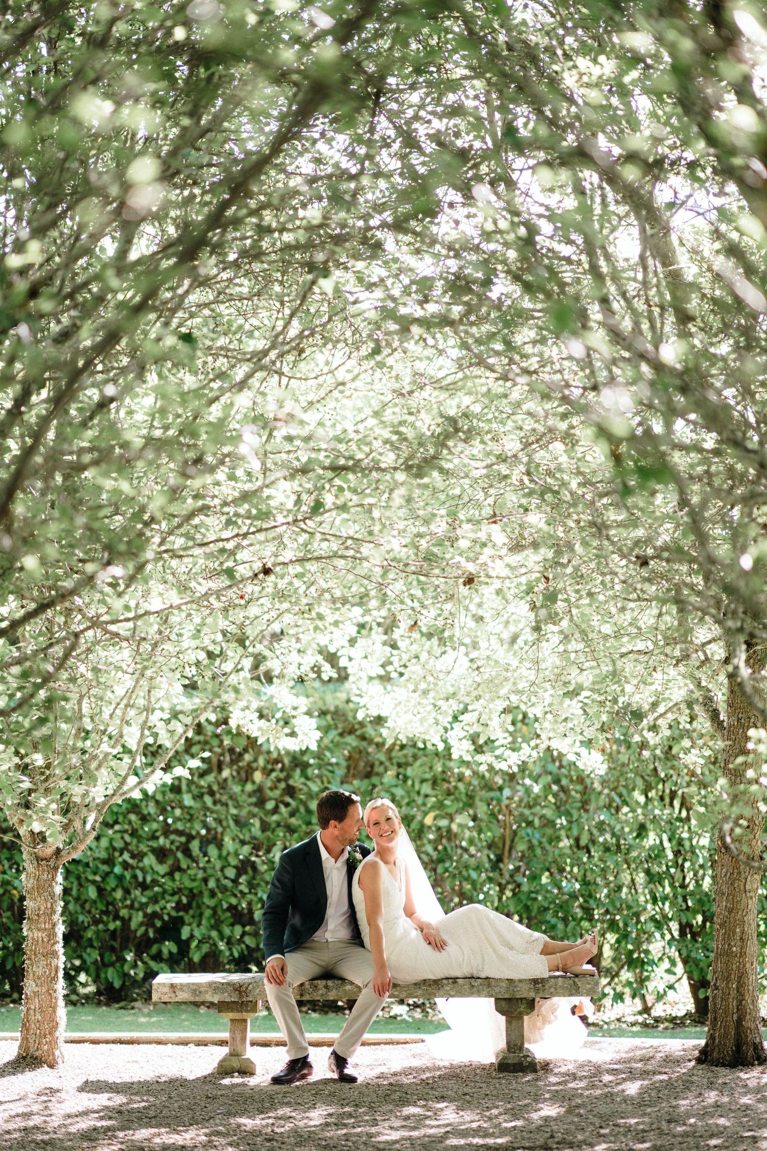 A couple shares an intimate moment beneath blooming trees in a garden setting.