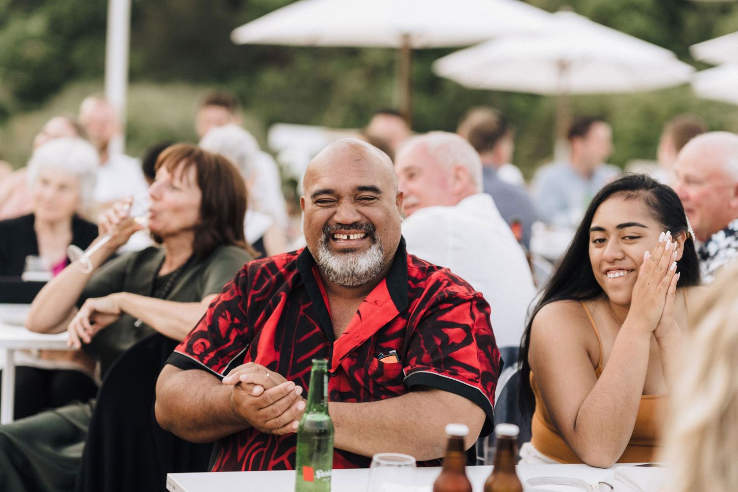 Wedding guests enjoying themselves during an outdoor reception under white umbrellas.
