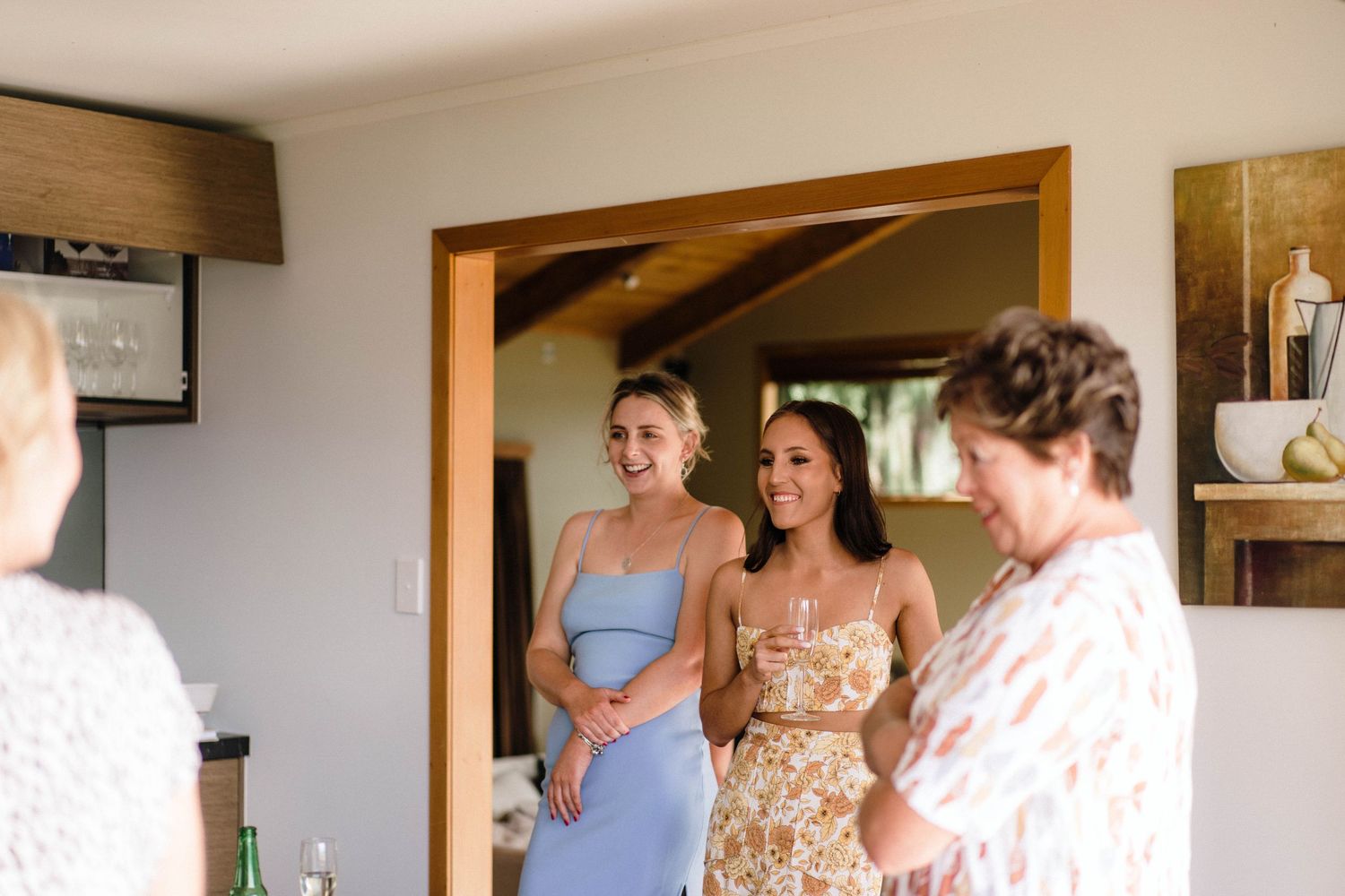 Wedding party members gathered in a doorway wearing pastel dresses during pre-ceremony preparations.
