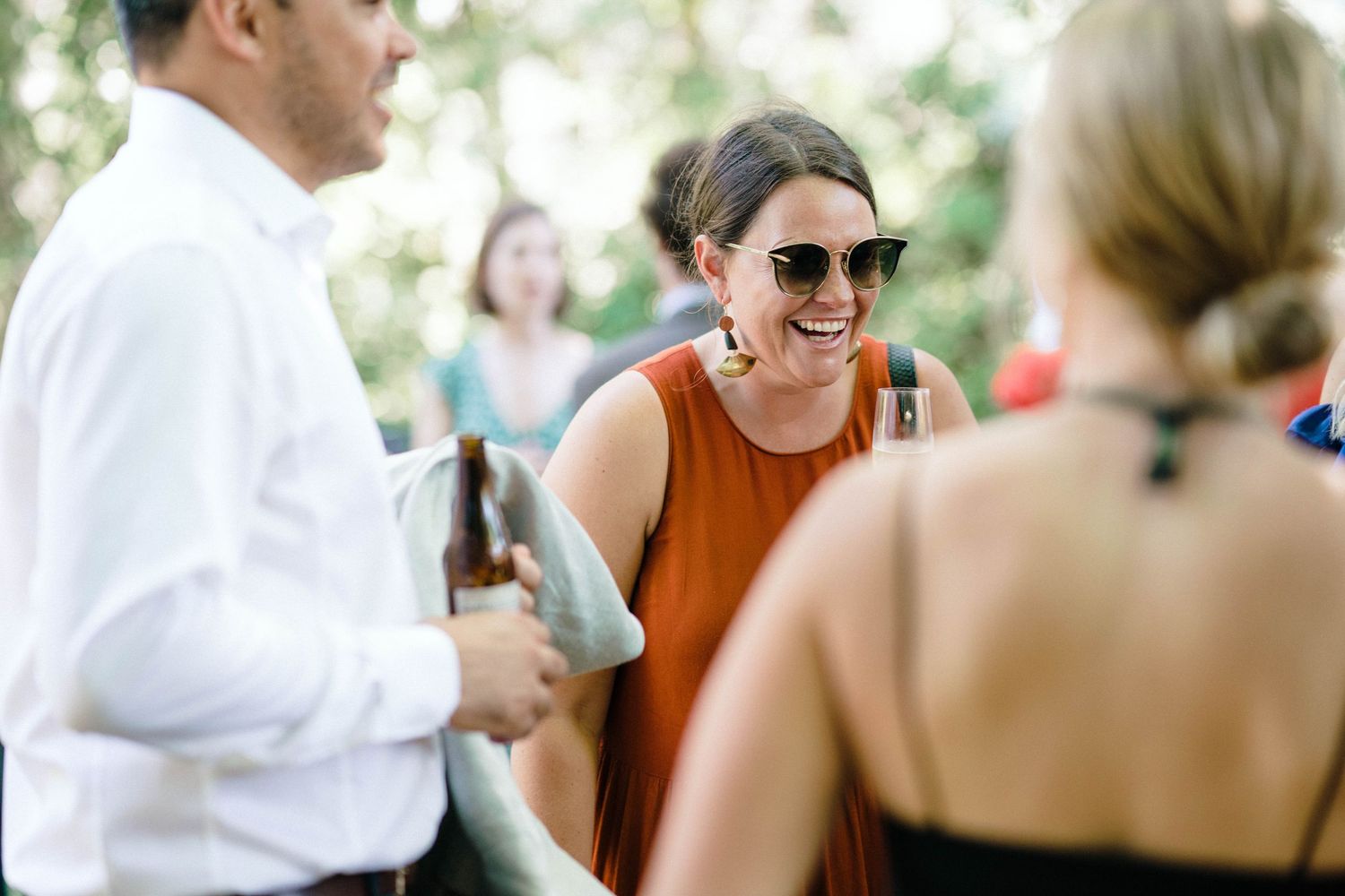 People enjoying conversation while seated outdoors at a casual gathering or party on a sunny day.