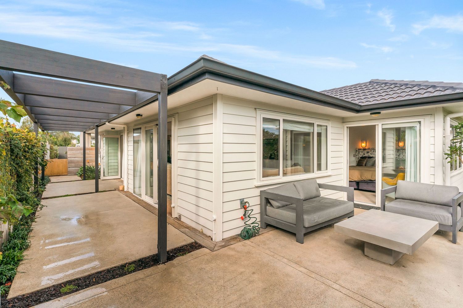 Multiple views of a modern house exterior with covered porch and grey decking areas.