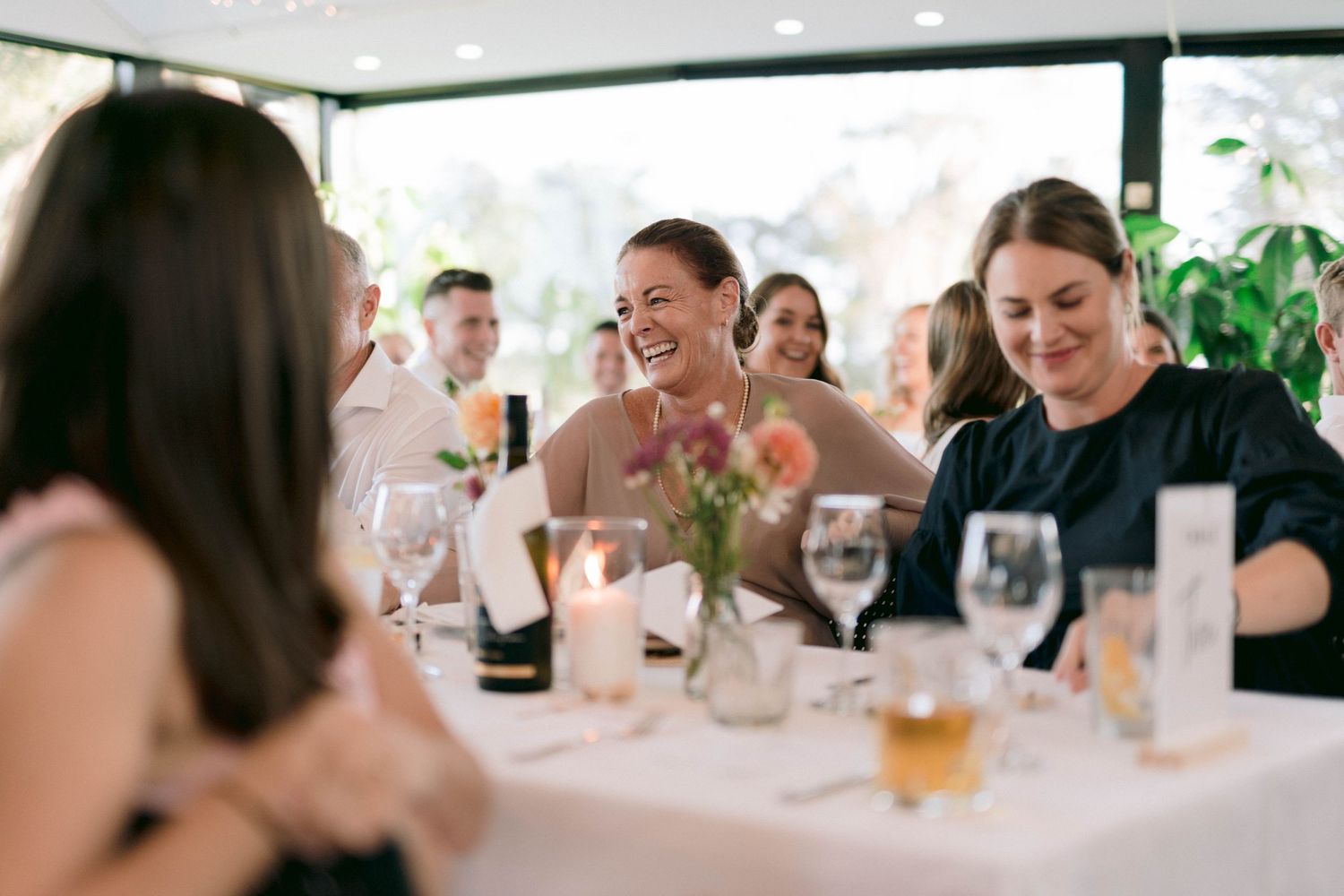 Guests enjoying a bright, modern restaurant setting with white tablecloths and panoramic windows during daytime dining.