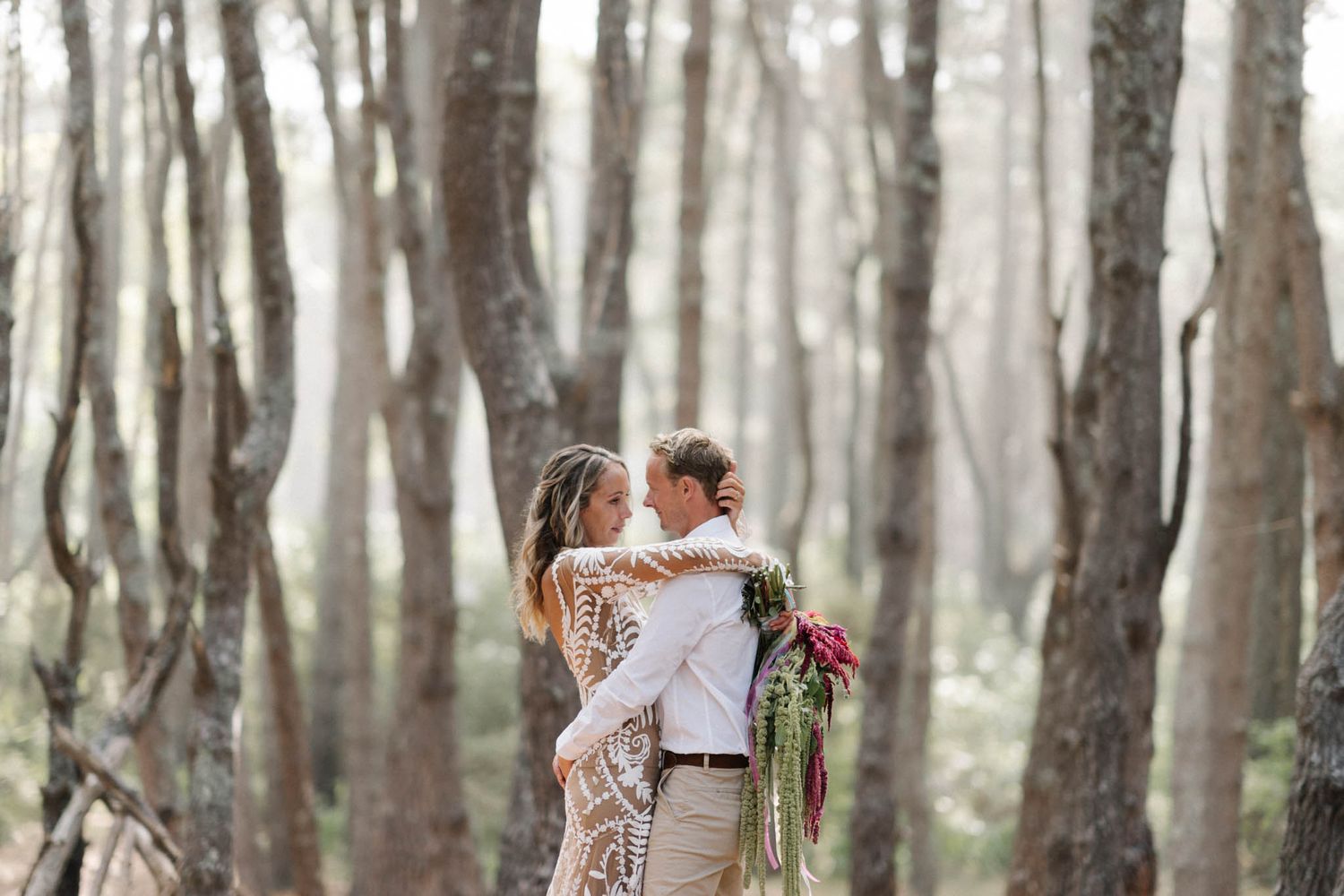 A couple embraces in a dreamy woodland setting during a romantic outdoor photo session.