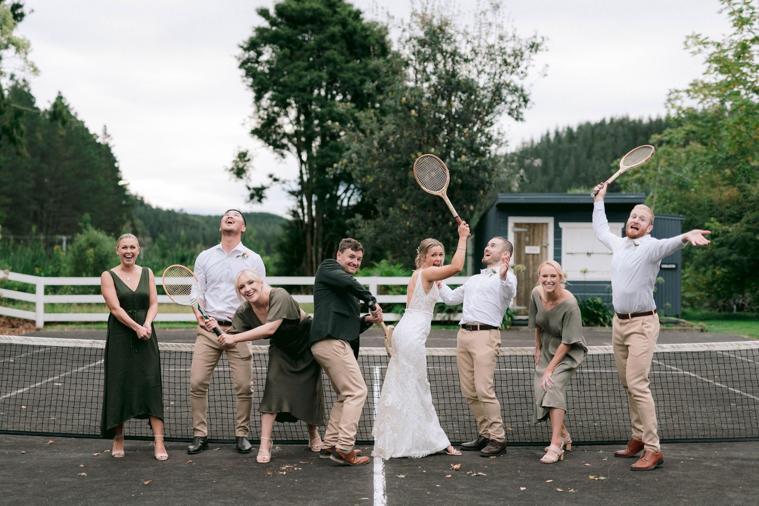 Outdoor tennis court transformed into a playful wedding reception space with guests dancing.