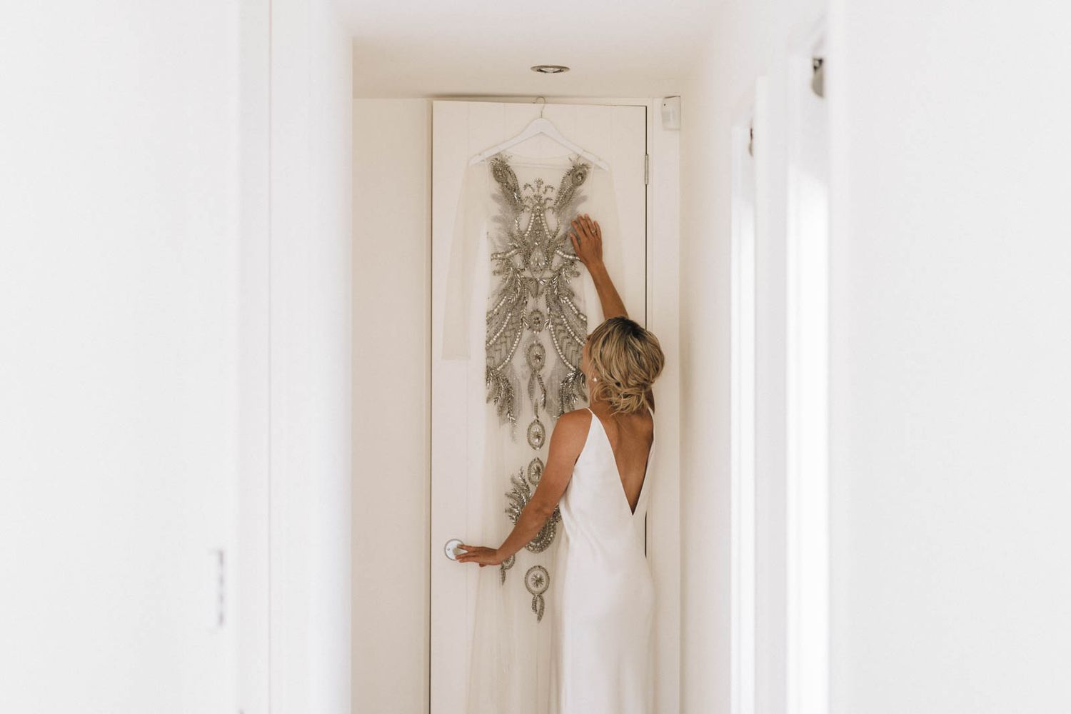 Artistic fashion photo showing a person in heels posing dramatically against a white door with framed wall art.