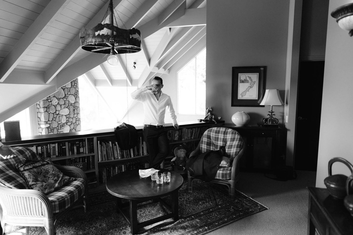 A cozy reading nook in the attic features shelves of books, sloped ceilings and comfortable seating near a window.