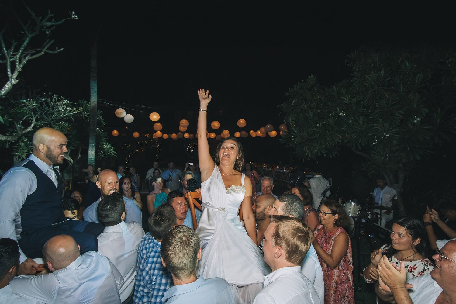 Wedding guests dancing and celebrating on an outdoor dance floor at night.
