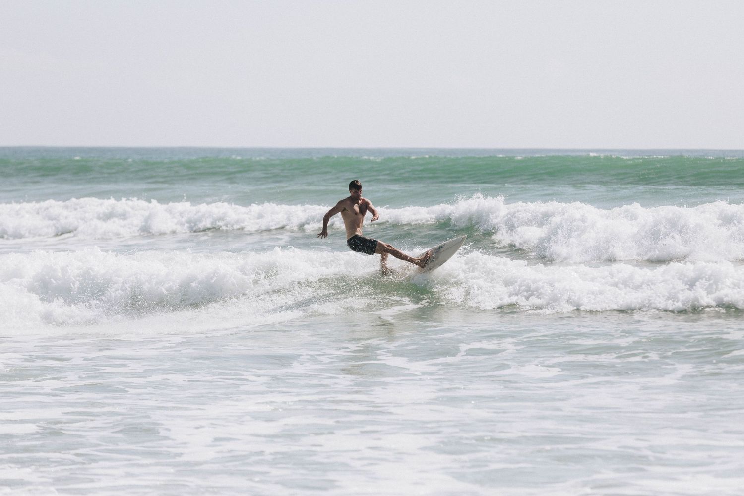 Surfer rides ocean waves in sequence of action shots showing athletic moves on surfboard.