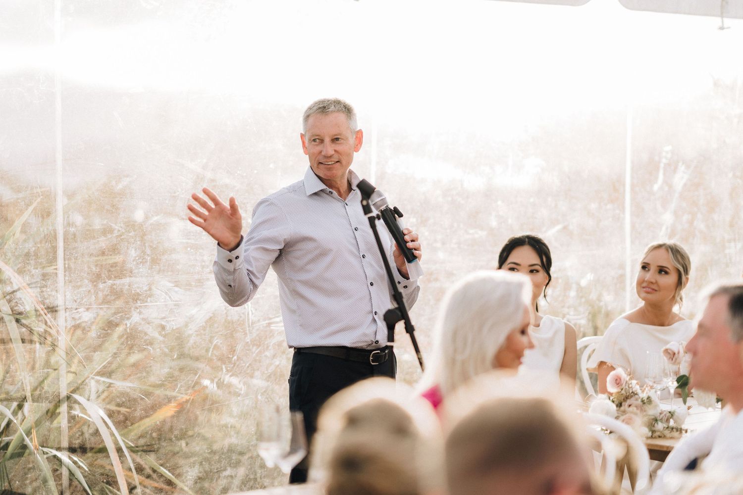Outdoor wedding celebration with guests applauding during sunny coastal ceremony.