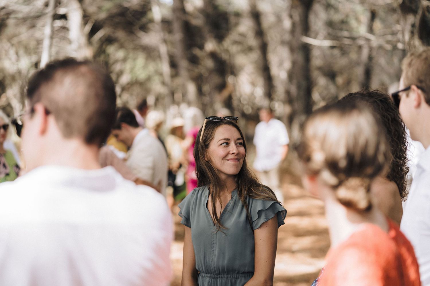 A blurred wedding party mingling outdoors in a natural setting with soft lighting and warm autumn colors.