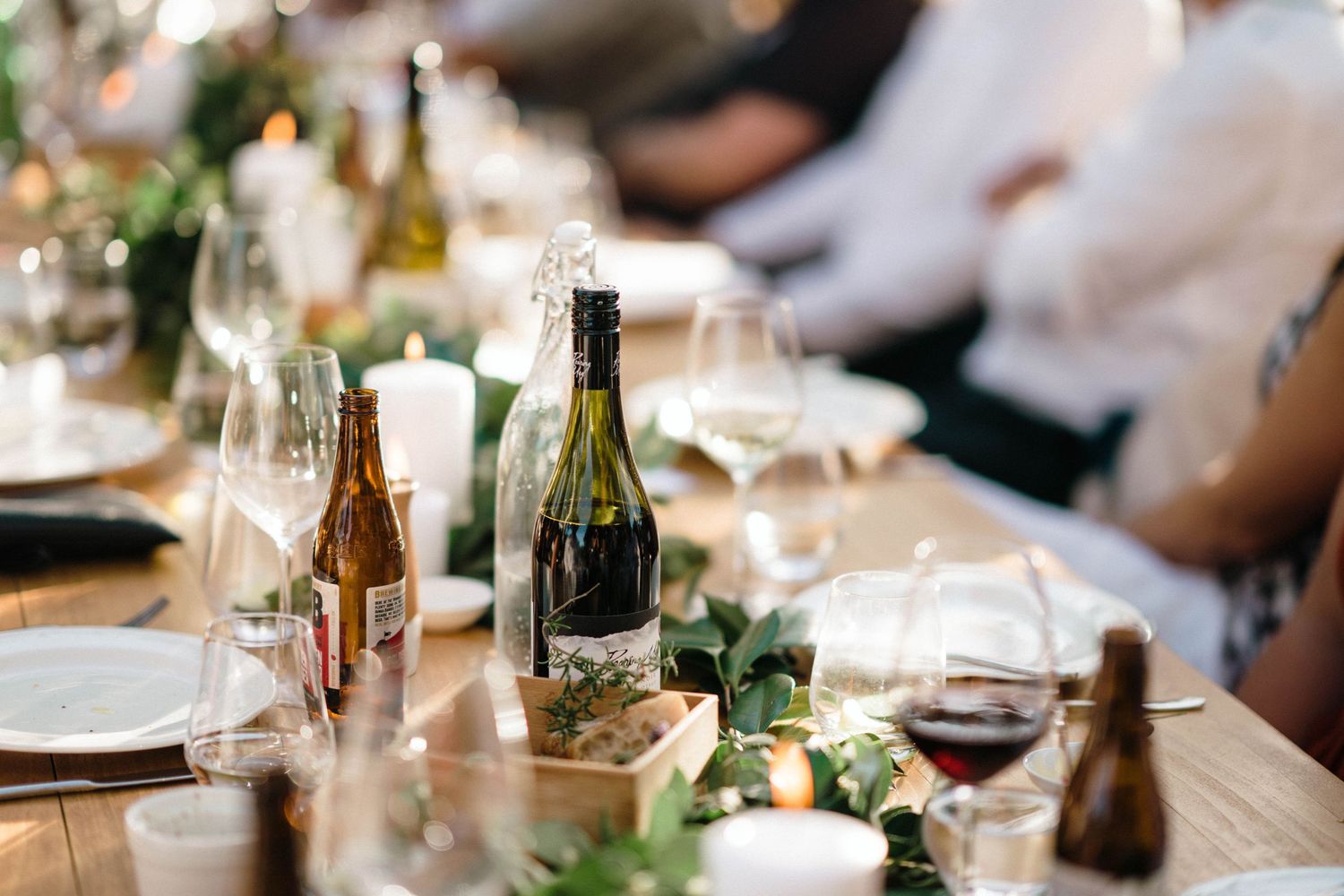 Wedding reception table settings with wine bottles and floral centerpieces.