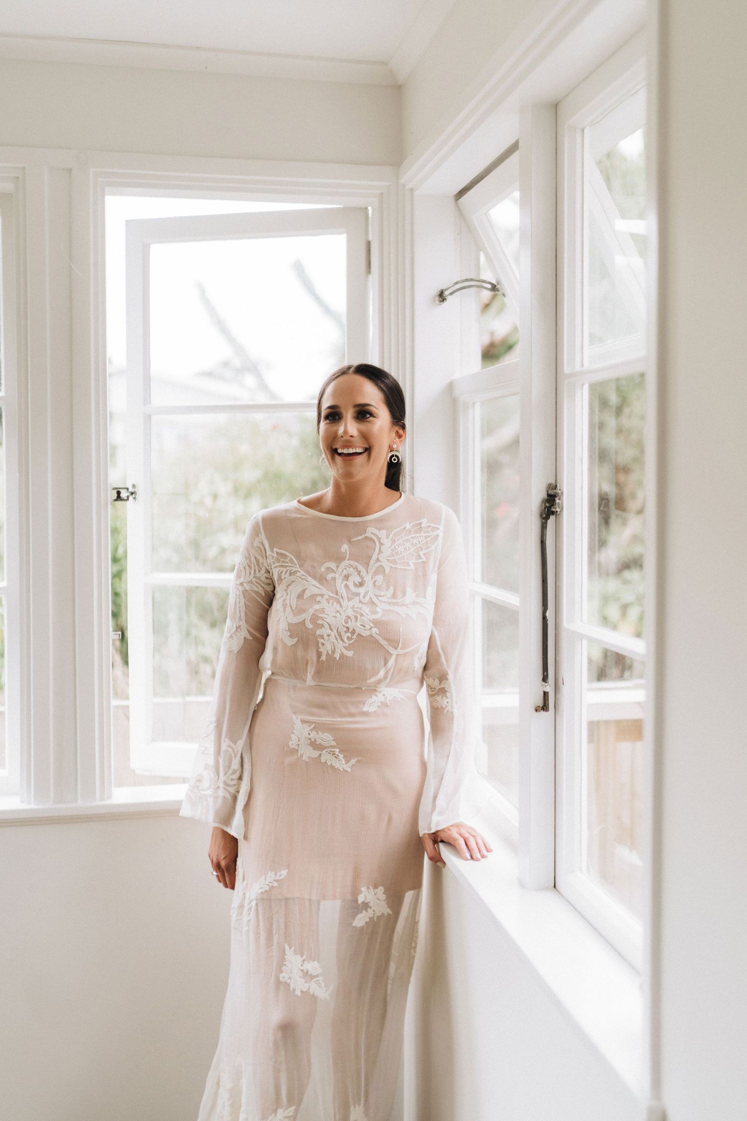 Sunlit bridal portrait in a white room with large windows creating a dreamy atmosphere.