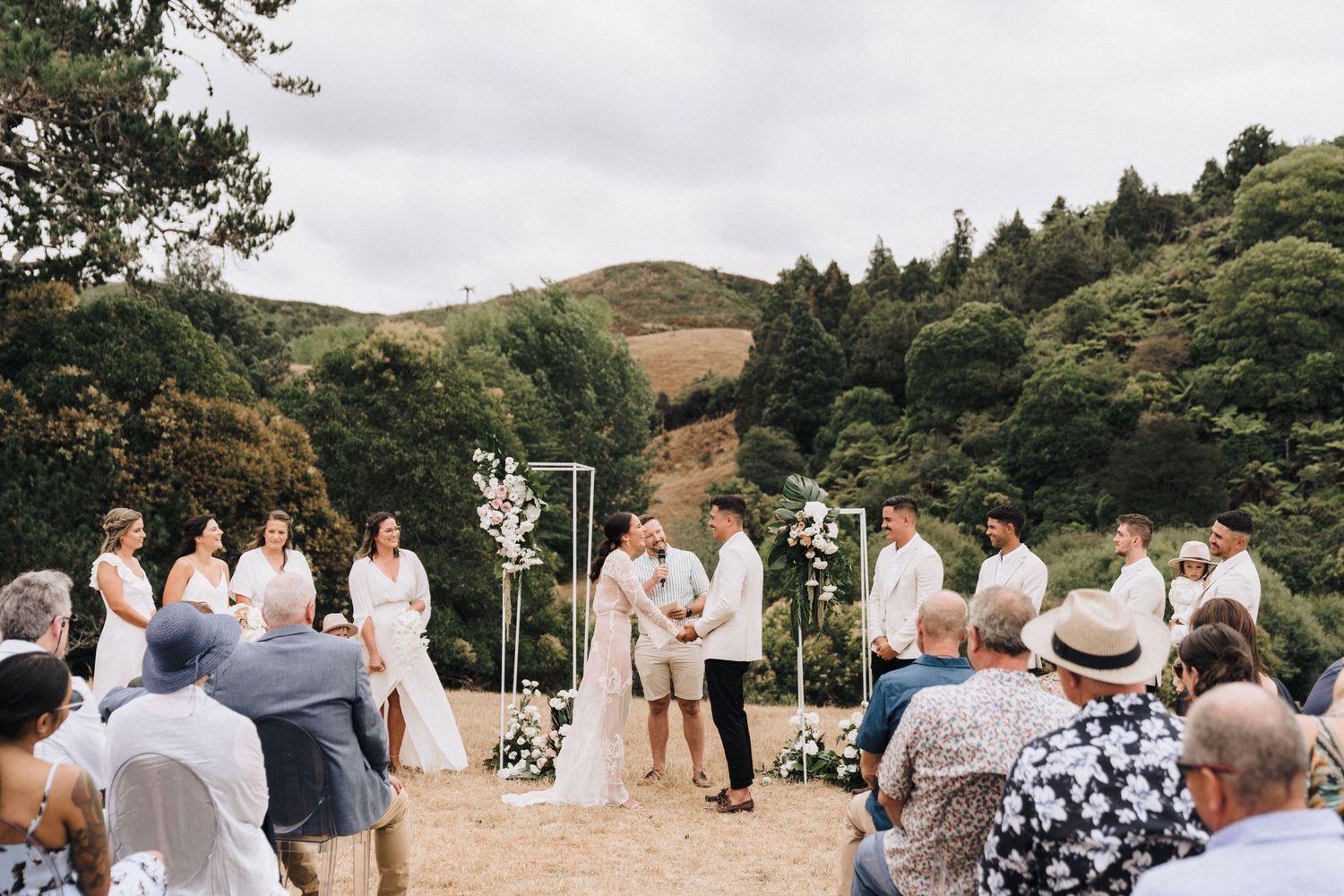 Wedding ceremony setup in a scenic mountain location with white floral decorations.