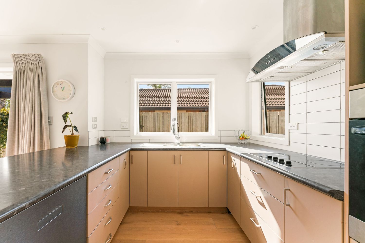 Contemporary U-shaped kitchen with dark countertops, beige cabinets and stainless steel appliances.
