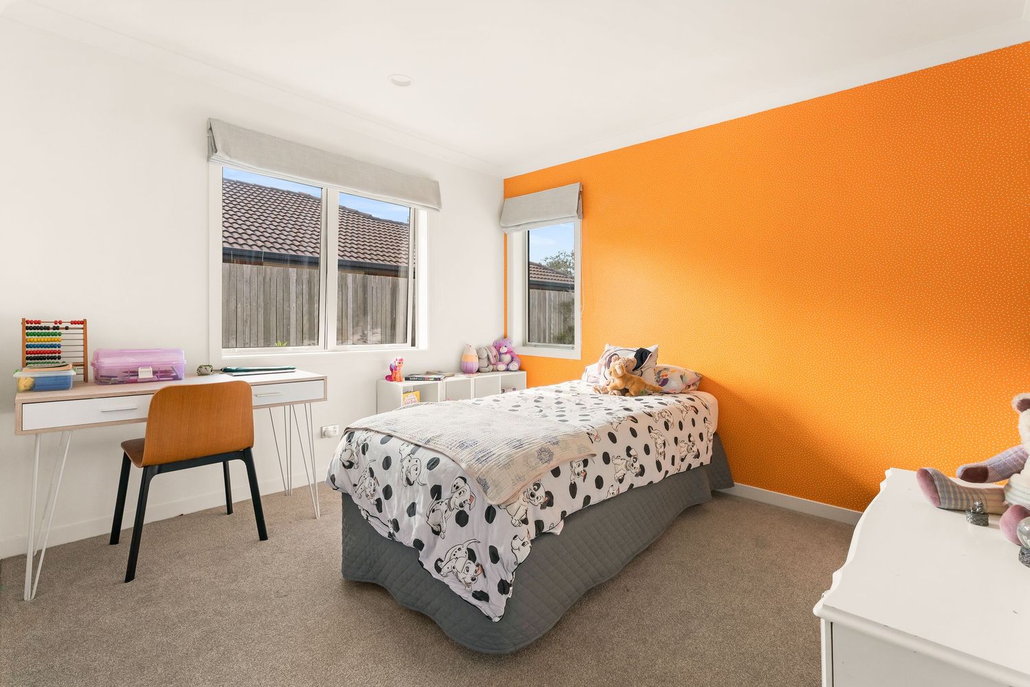 Orange accent wall brightens a cozy bedroom with contemporary furnishings and ample natural light.