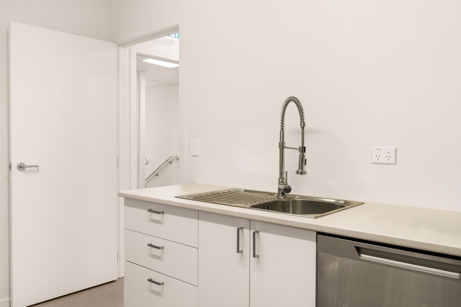 Clean white modern kitchen with sleek cabinetry and stainless steel sink.