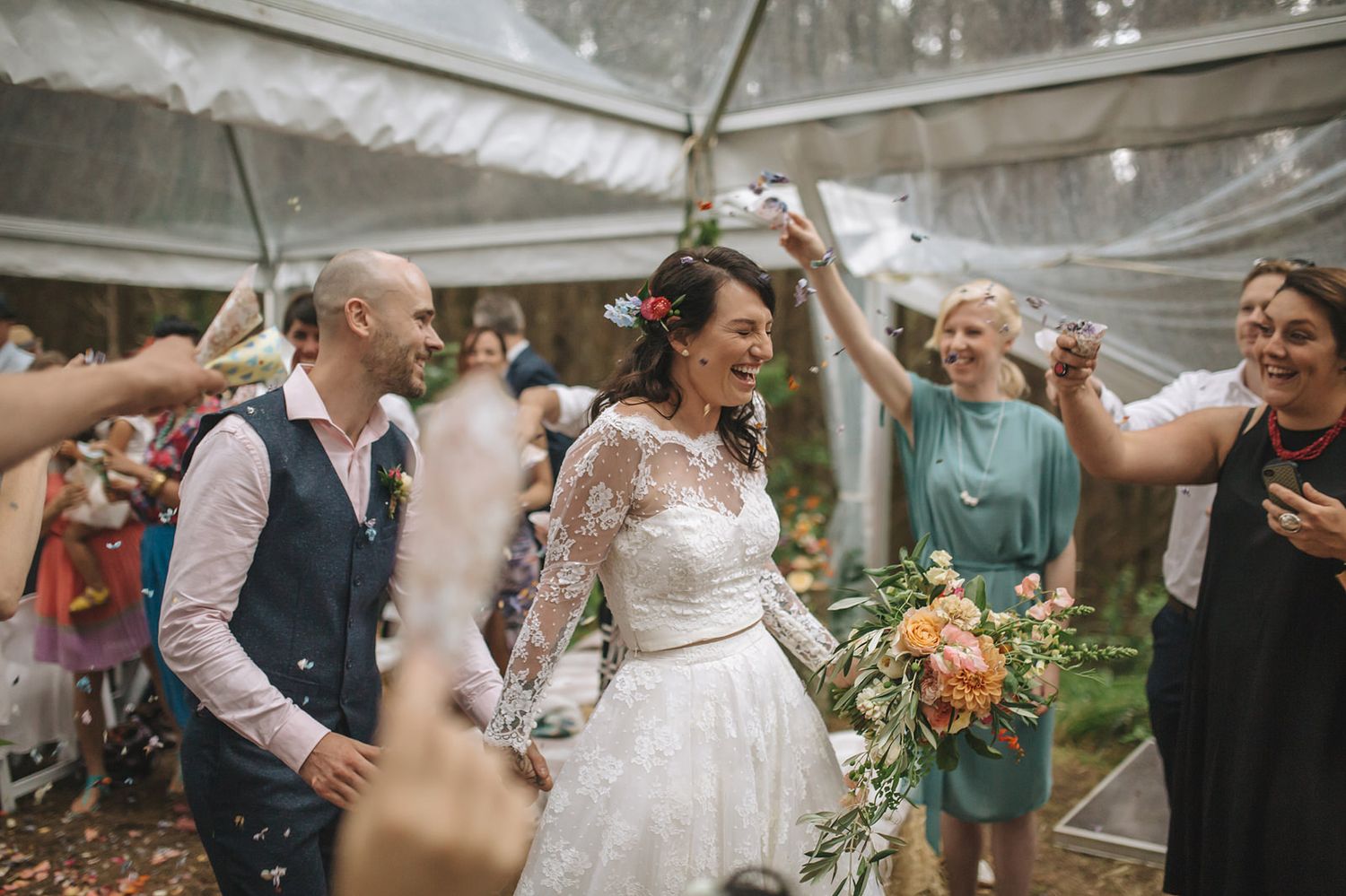 A joyful celebration unfolds inside a white tent venue with wedding guests enjoying the festivities and dancing.