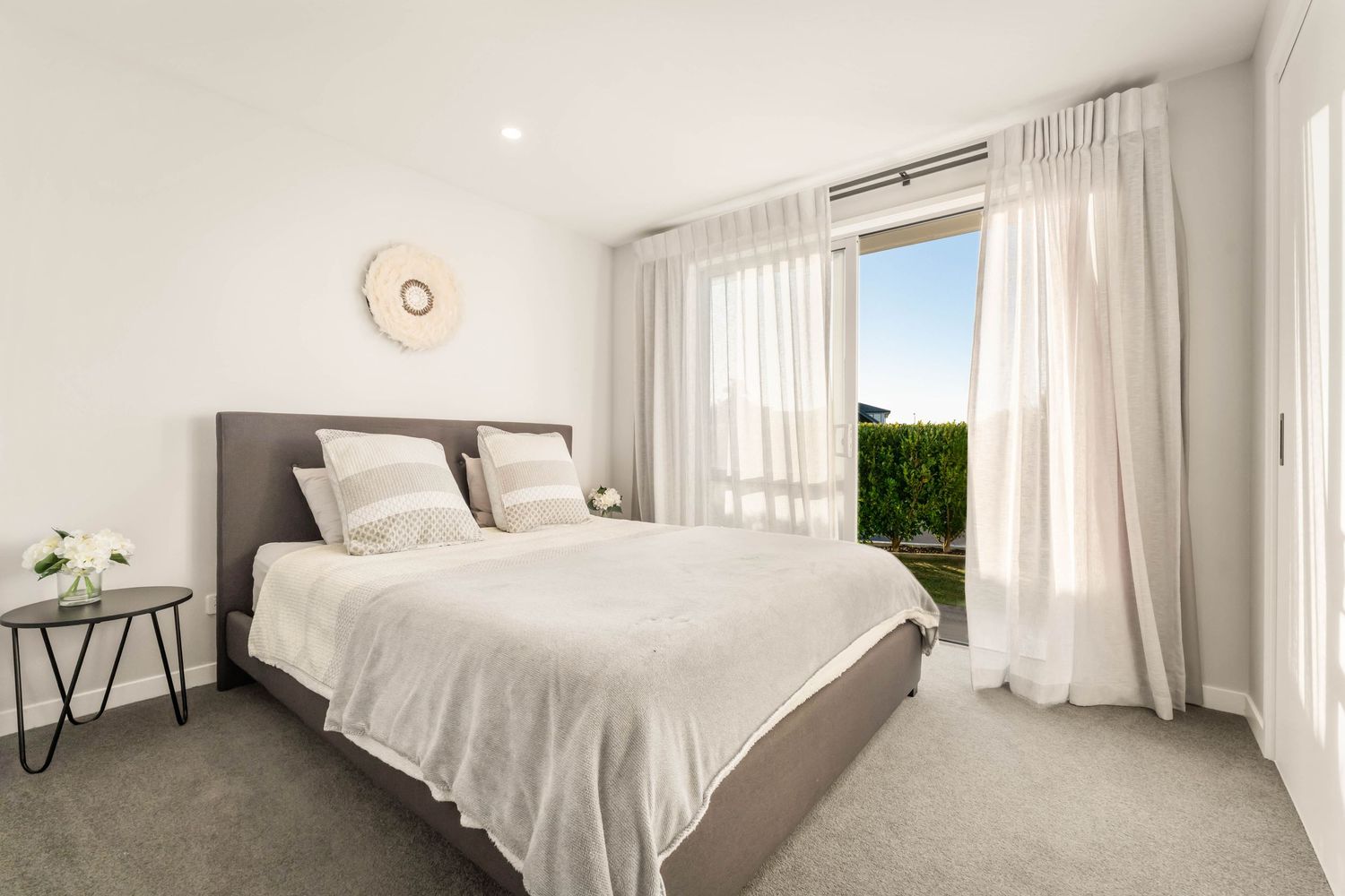 Serene bedroom with white bedding, natural light, and floor-length curtains.