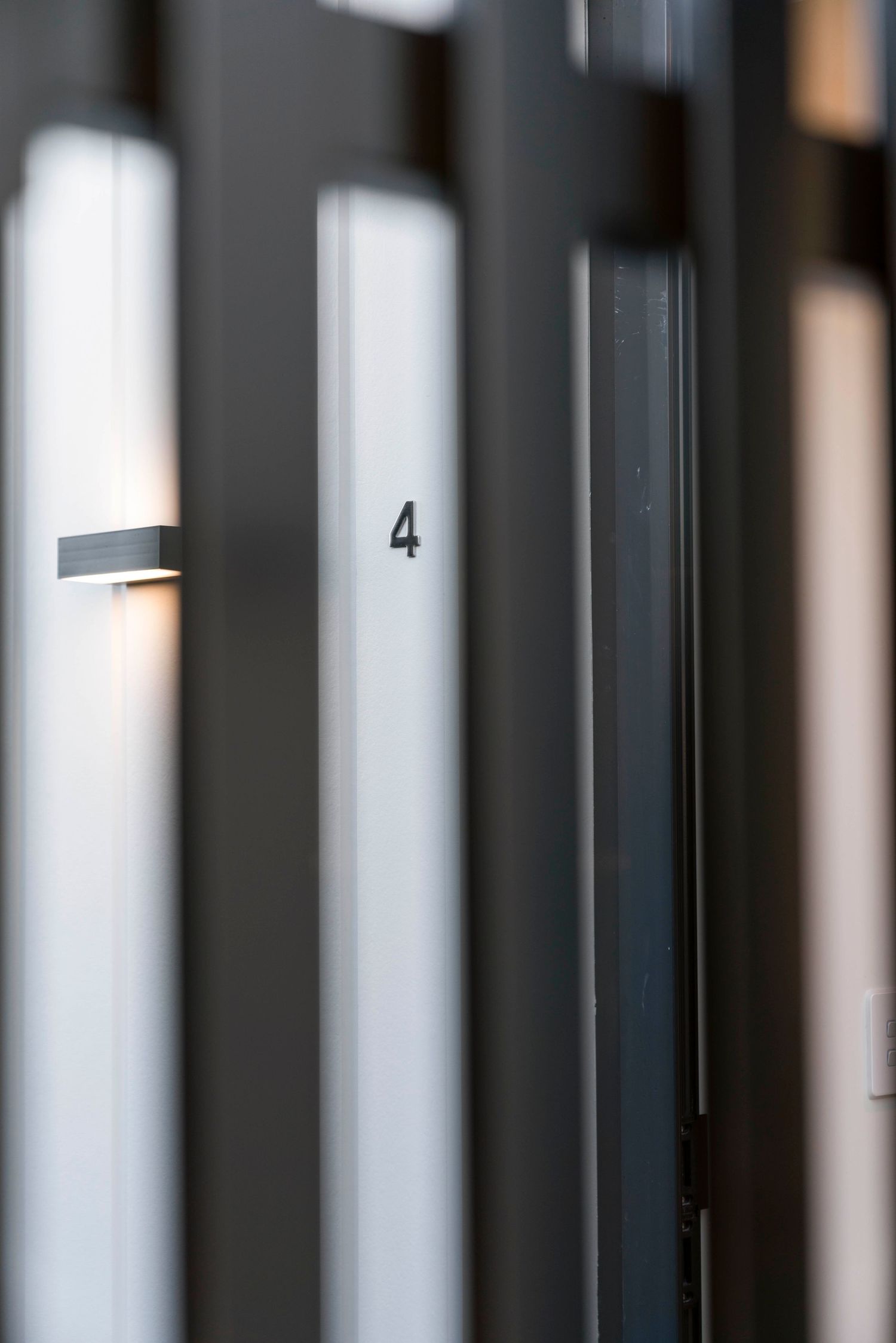 Minimalist architectural detail showing number 4 on white column with dramatic lighting.