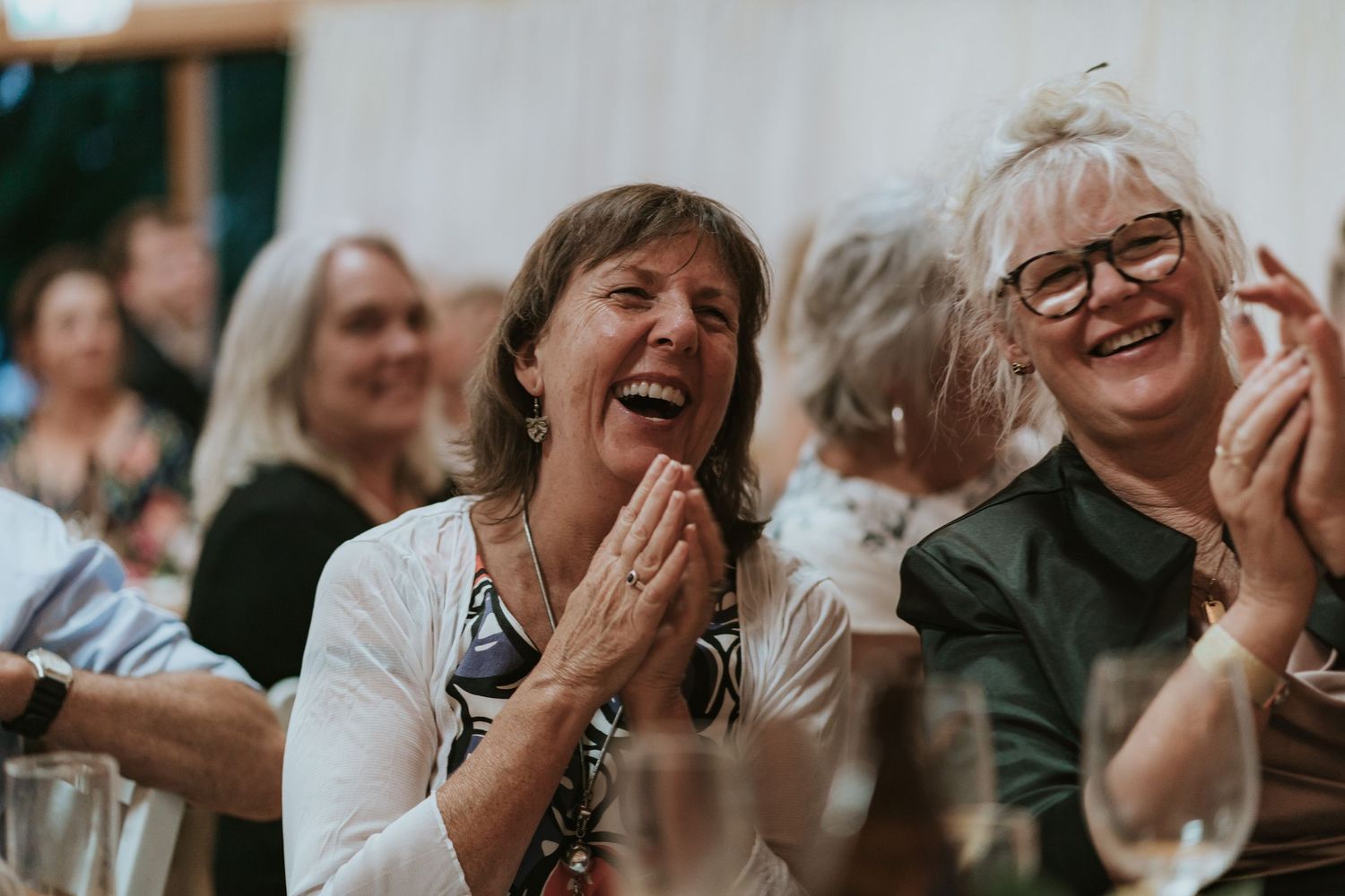 Enthusiastic audience members laugh and clap during a live performance with joyful expressions.