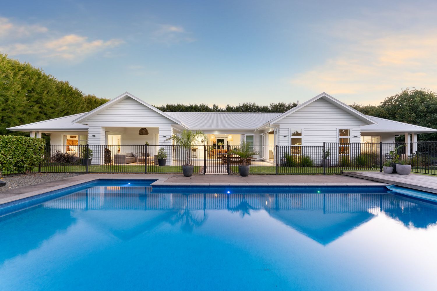 Stunning white villa with pool reflecting warm sunset light and symmetric architecture.