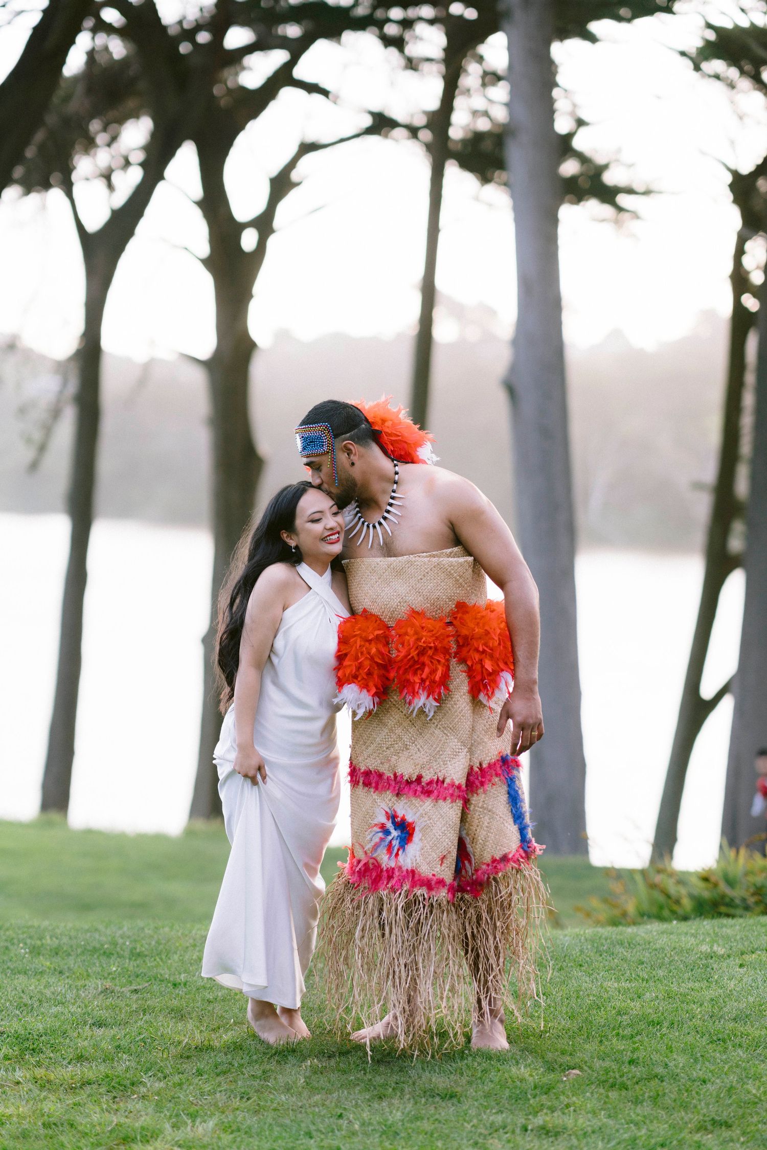 Fun couples photo session in a park with one person wearing a grass skirt and tropical costume.