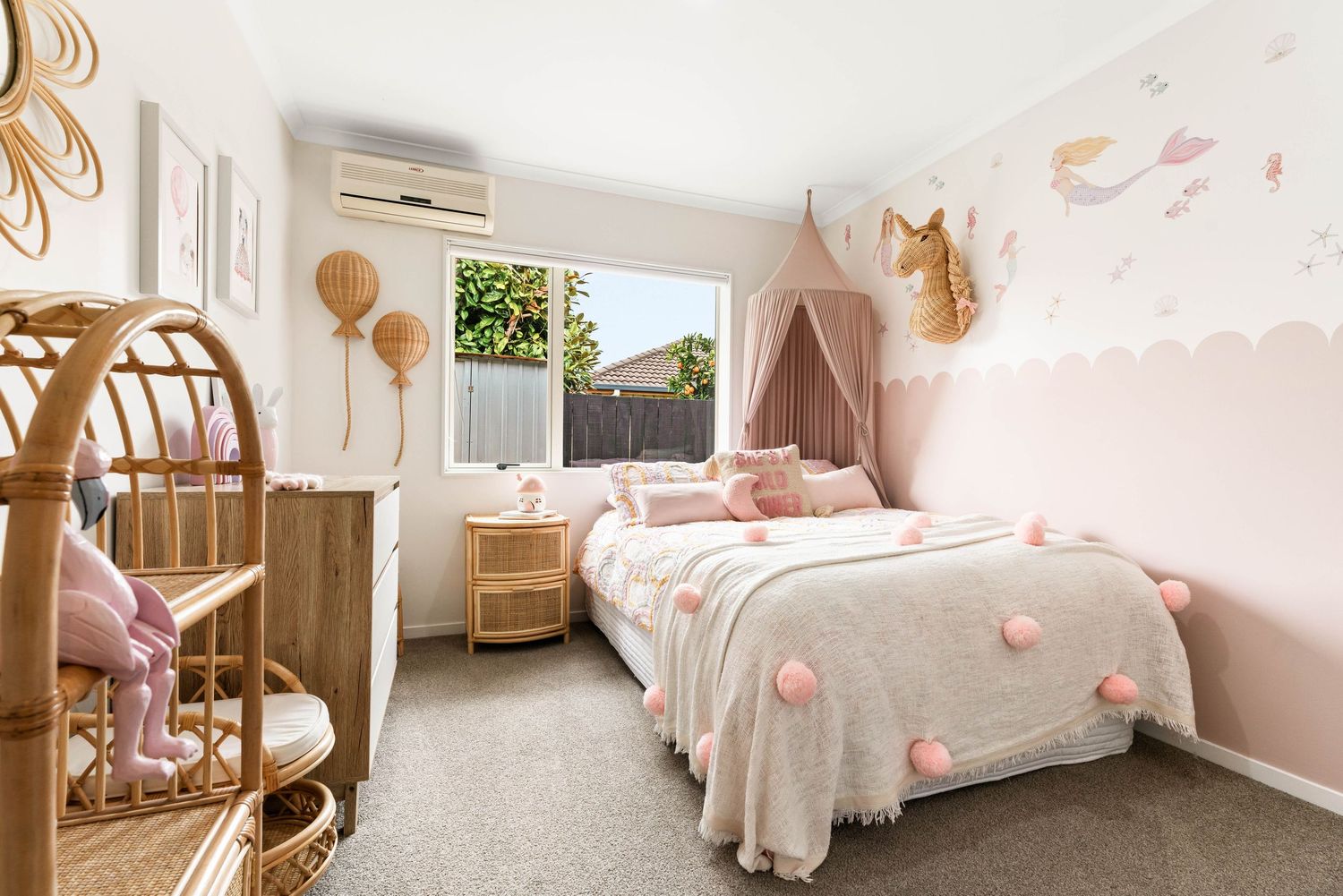 Spacious bedroom with soft pink walls, floral bedding, and natural lighting flowing through windows.
