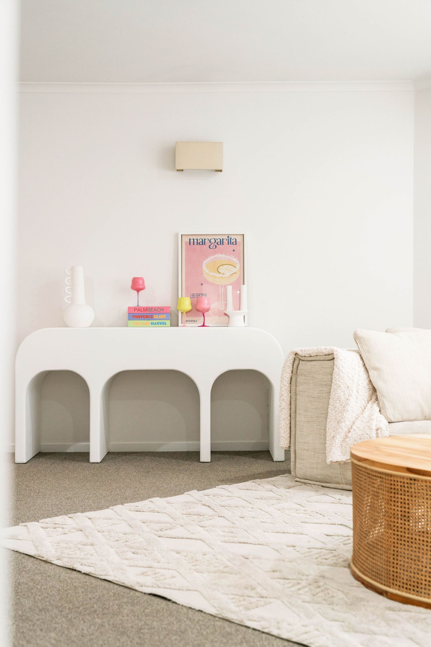 Minimalist white room with curved archways, rattan furniture, and plush carpet creates a serene nursery space.