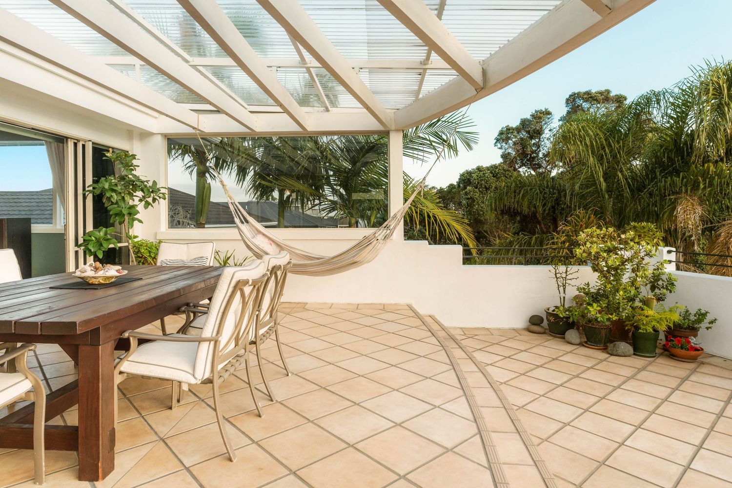 Modern covered patio with tiled flooring and glass ceiling panels letting in natural light.