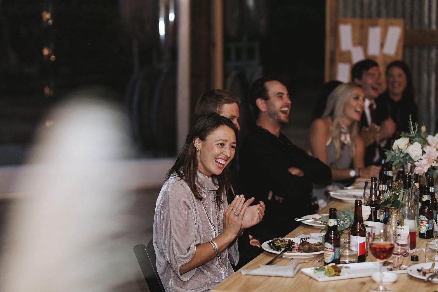 A candid sequence of black and white photos showing people laughing and enjoying a meal at a dinner party.