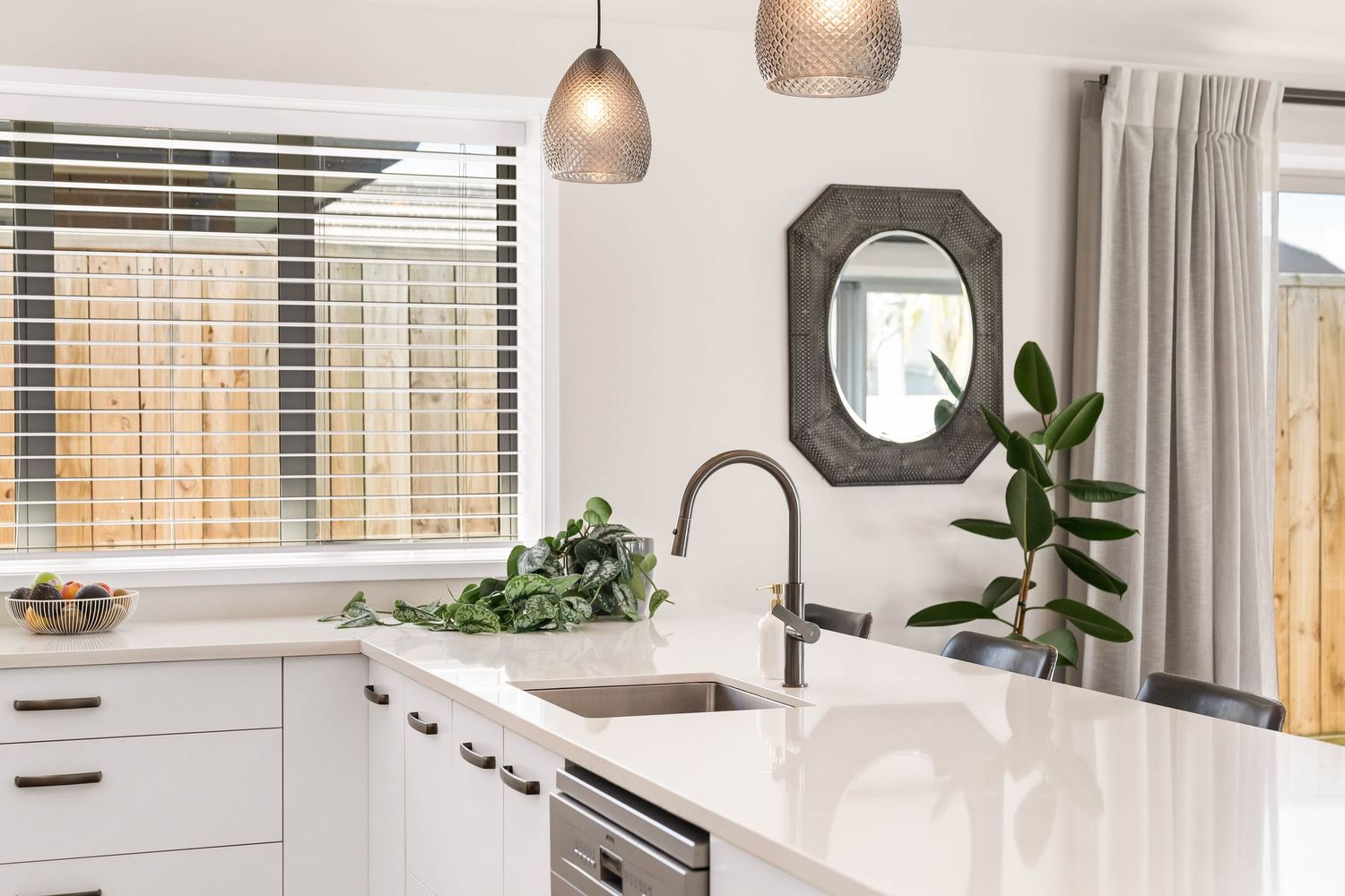 Contemporary open concept kitchen and living area with pendant lights and white cabinetry.