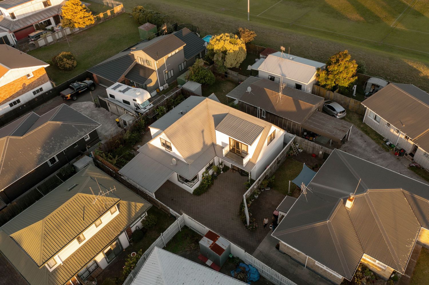 Aerial view of suburban houses with orange autumn trees in a residential neighborhood during sunset.