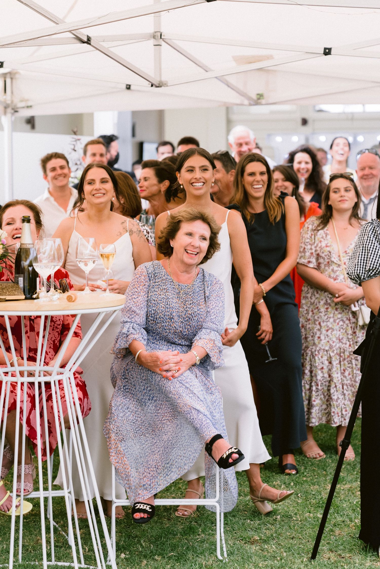 Wedding guests enjoying themselves under a white tent during outdoor reception.