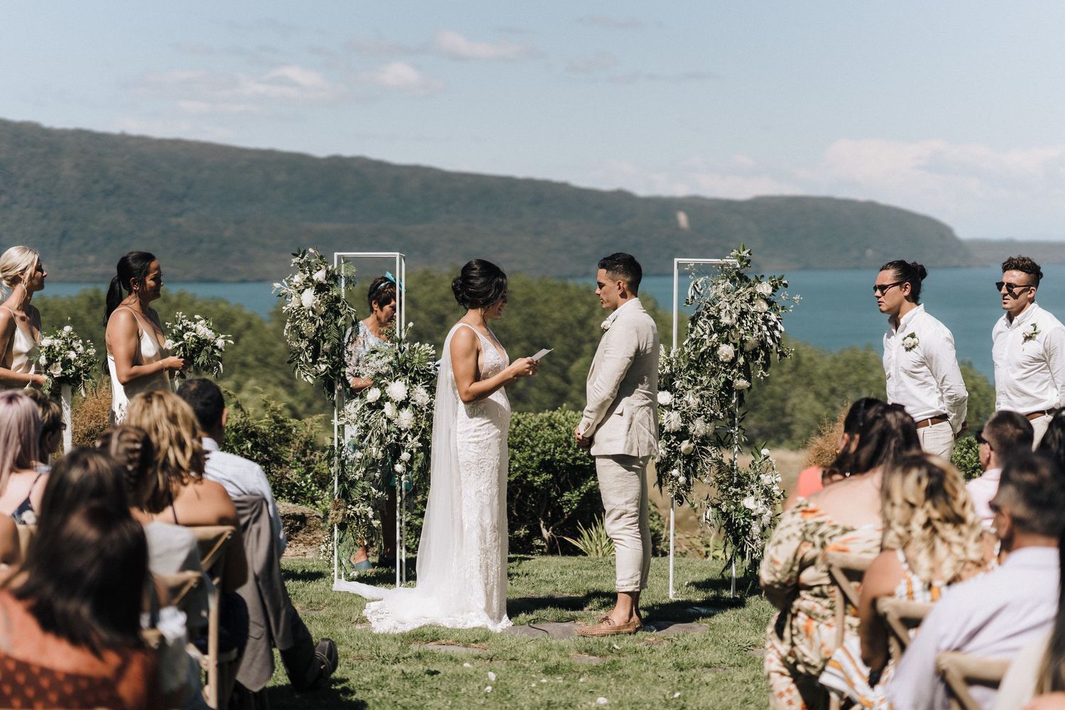 A scenic lakeside wedding ceremony with floral arch and mountain views.
